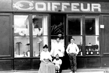 Le coiffeur et sa famille devant son magasin